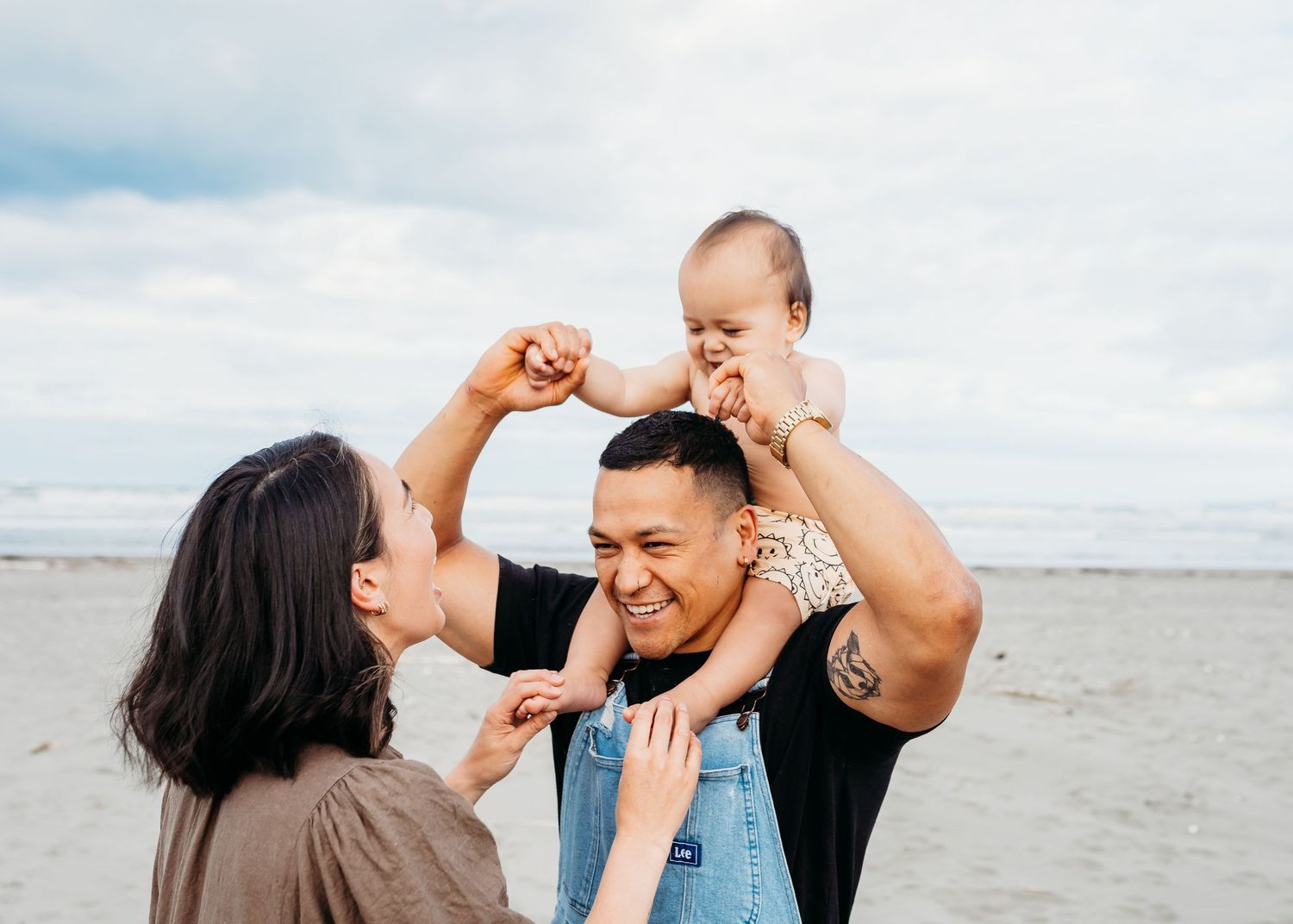 Joyful family moment on the beach as they play and laugh together.