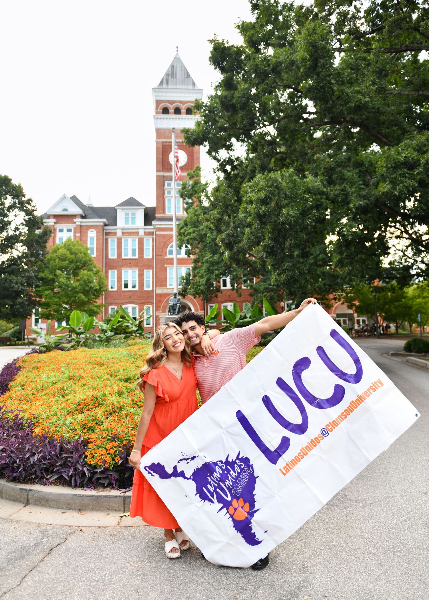 College campus scene with historic brick tower and purple LUCU banner in foreground.