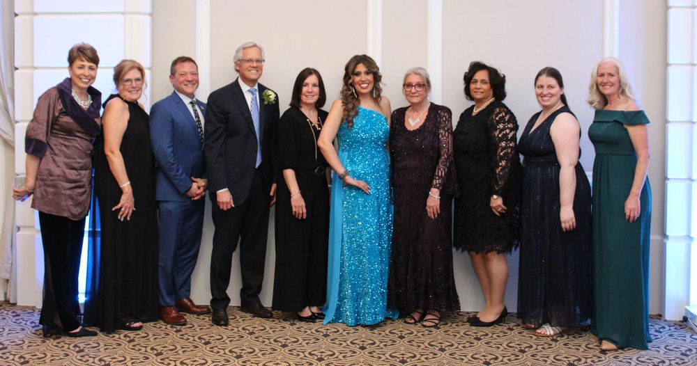 A lineup of formally dressed guests pose together at an elegant evening function.