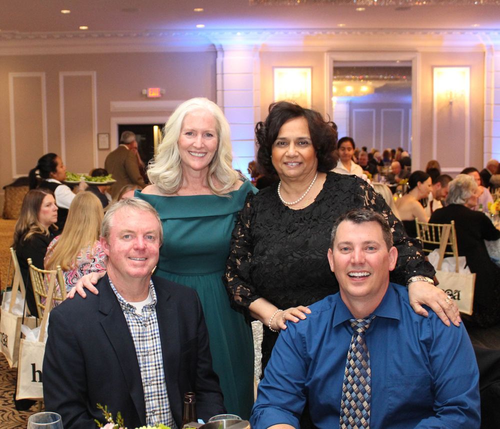 A group of four people pose together at a formal event in an elegant ballroom setting.