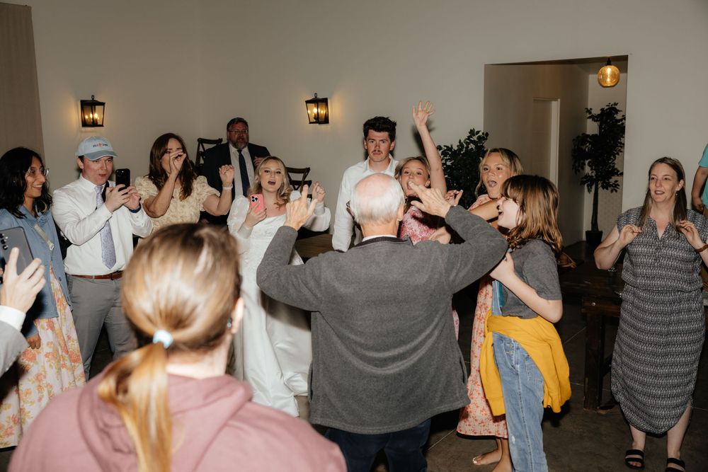 Joyful wedding reception guests dance and celebrate together inside elegant venue.