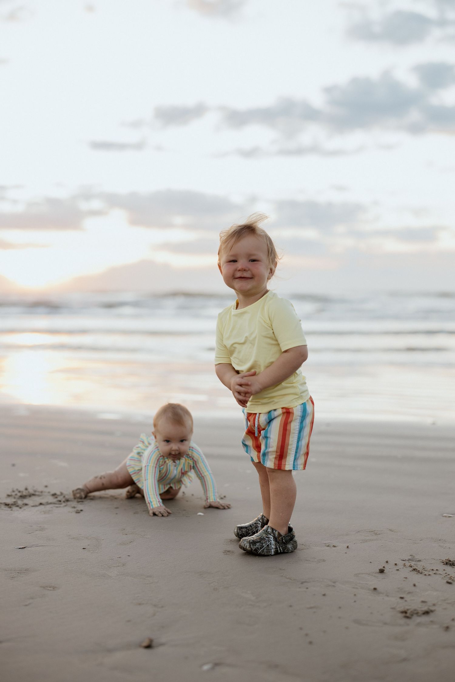 Two children playing together on beach at sunset.
