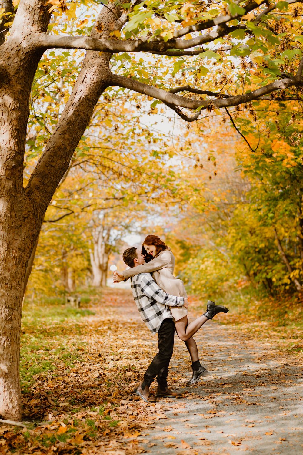 A romantic autumn scene in a park with fall foliage and golden leaves scattered along a winding path.