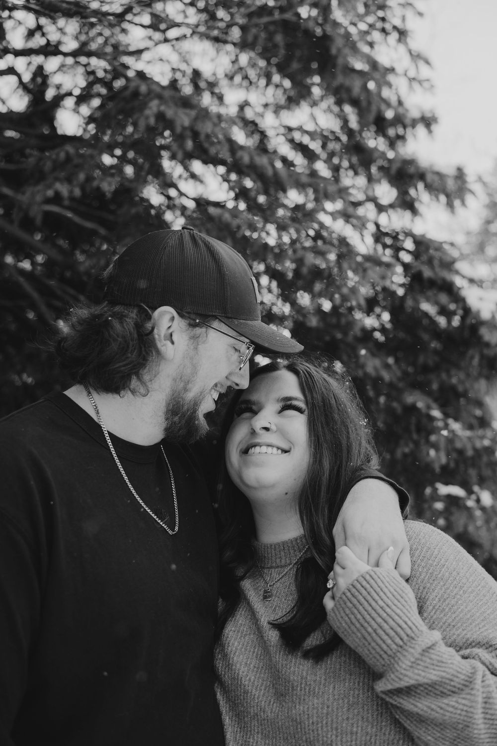 Black and white photo sequence of a couple in sweaters sharing intimate moments outdoors with trees in background.