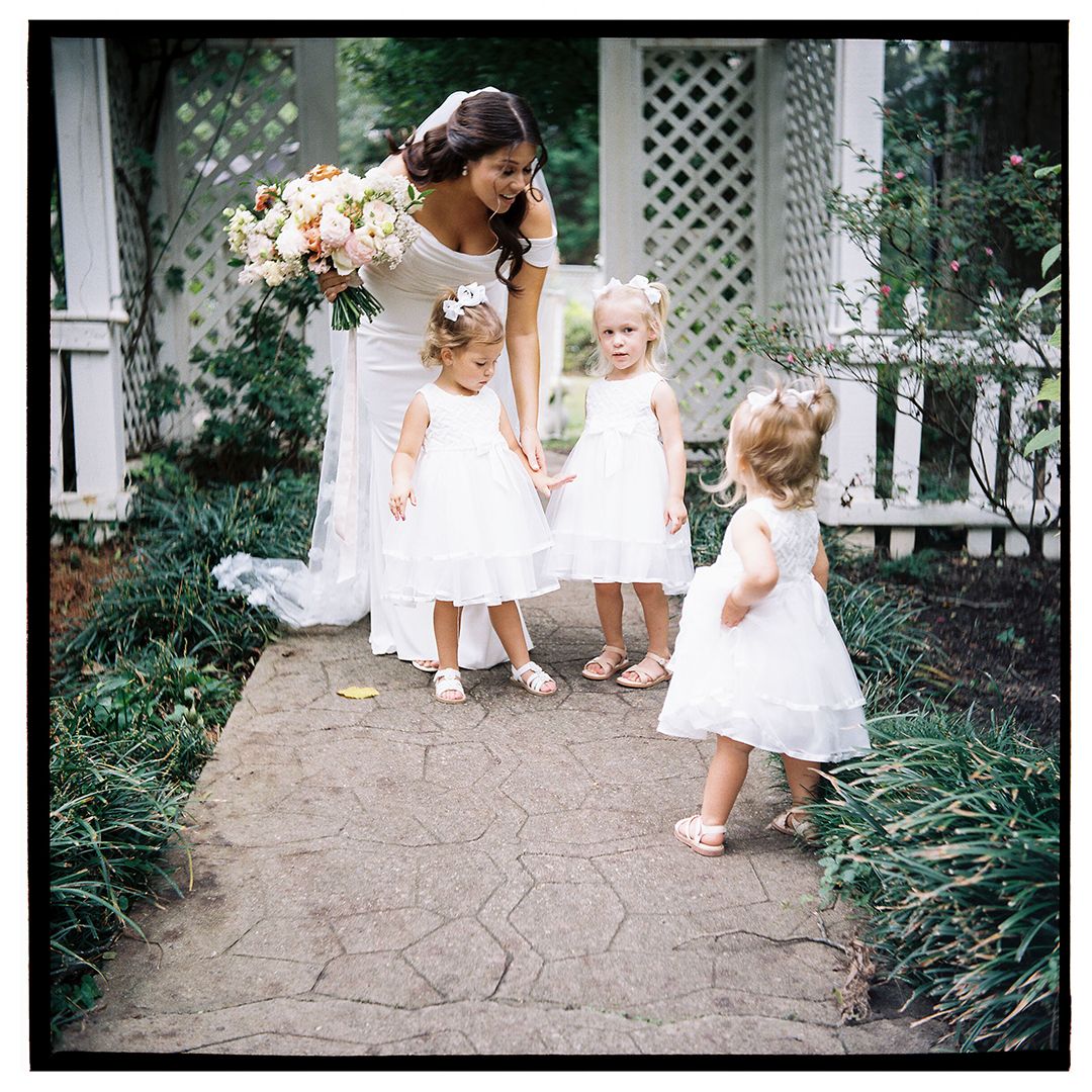 Sweet moments captured on stone pathway with white dresses and garden setting.