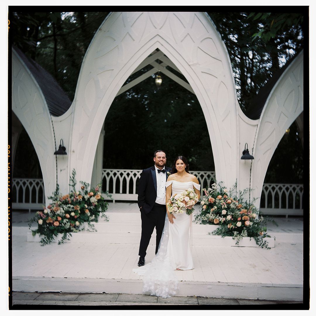 Wedding ceremony setup with gothic arches decorated with floral arrangements.