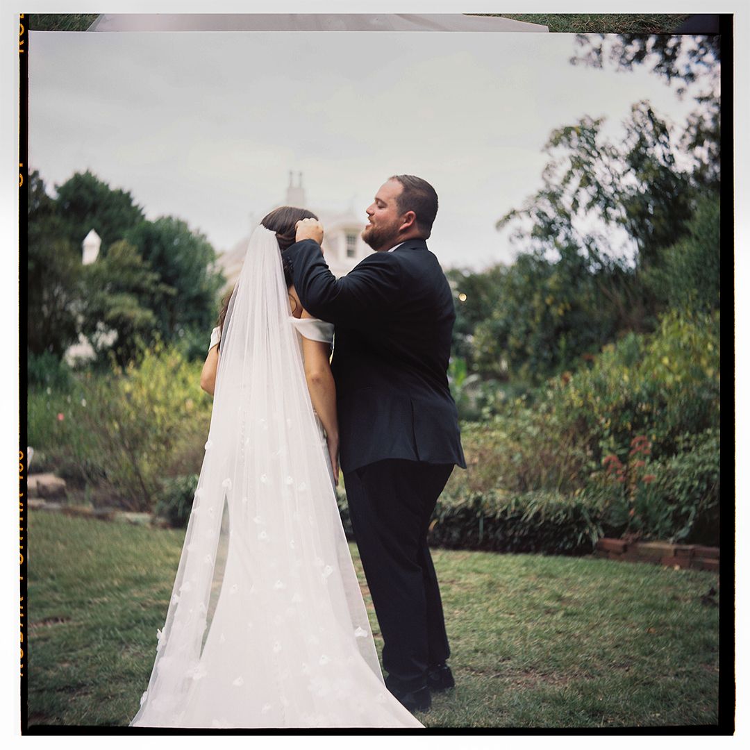 Wedding photography session in garden setting with flowing veil.