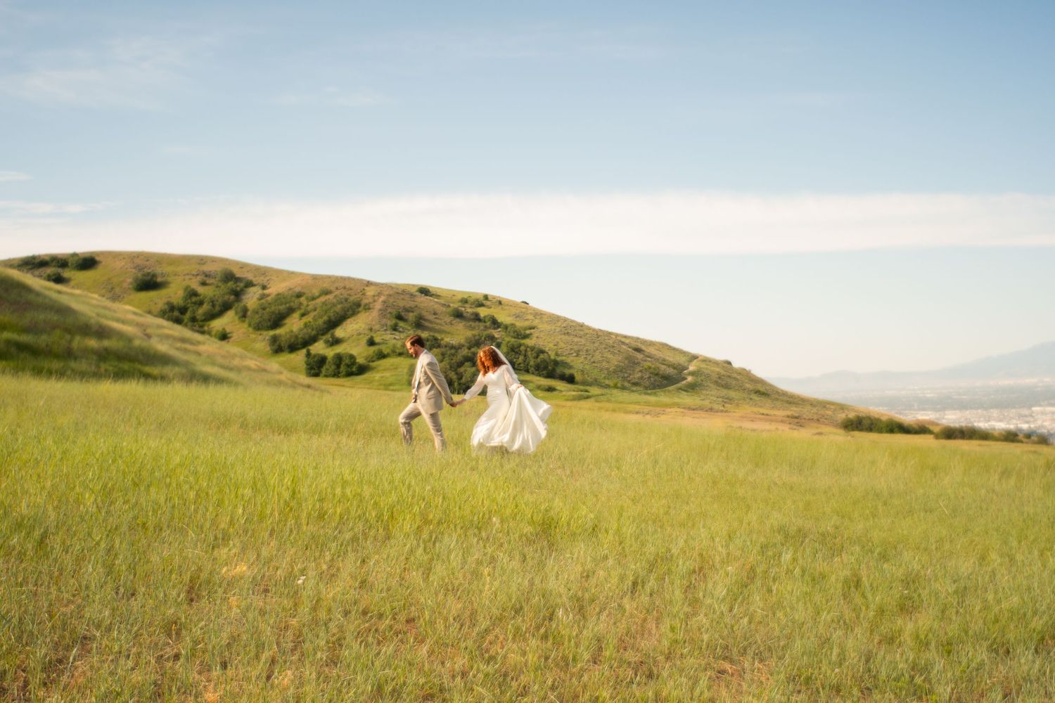 A bride and groom walk dramatically across a field in a cinematic photo in Salt Lake City Utah.