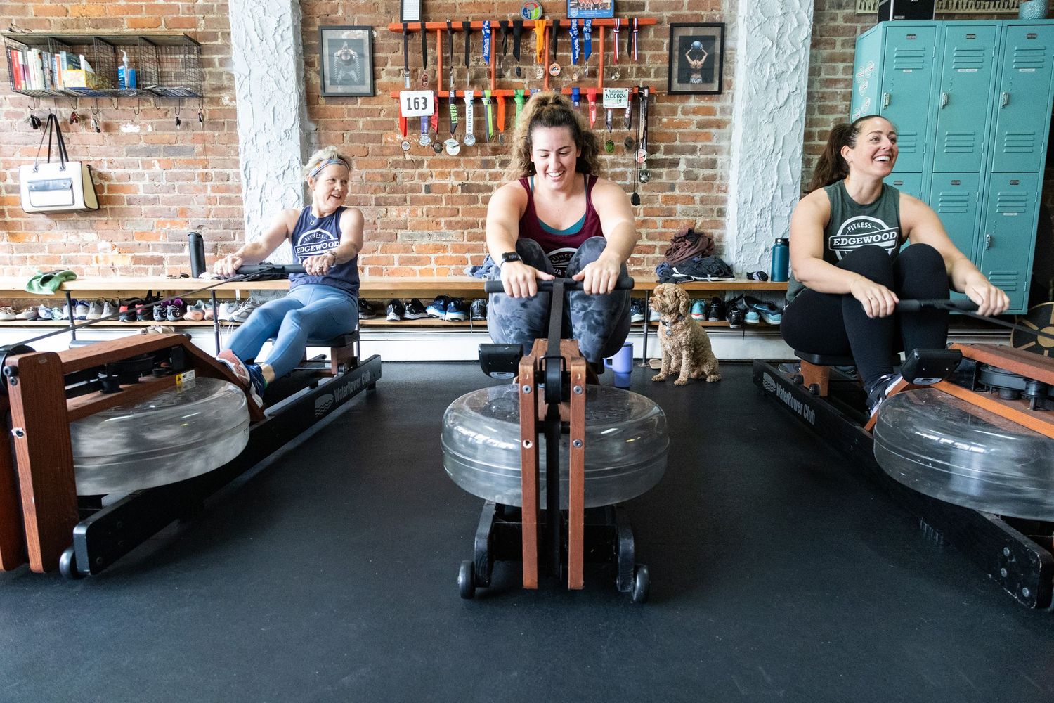 Athletes perform stretching exercises on yoga mats in a rustic brick-walled fitness studio.