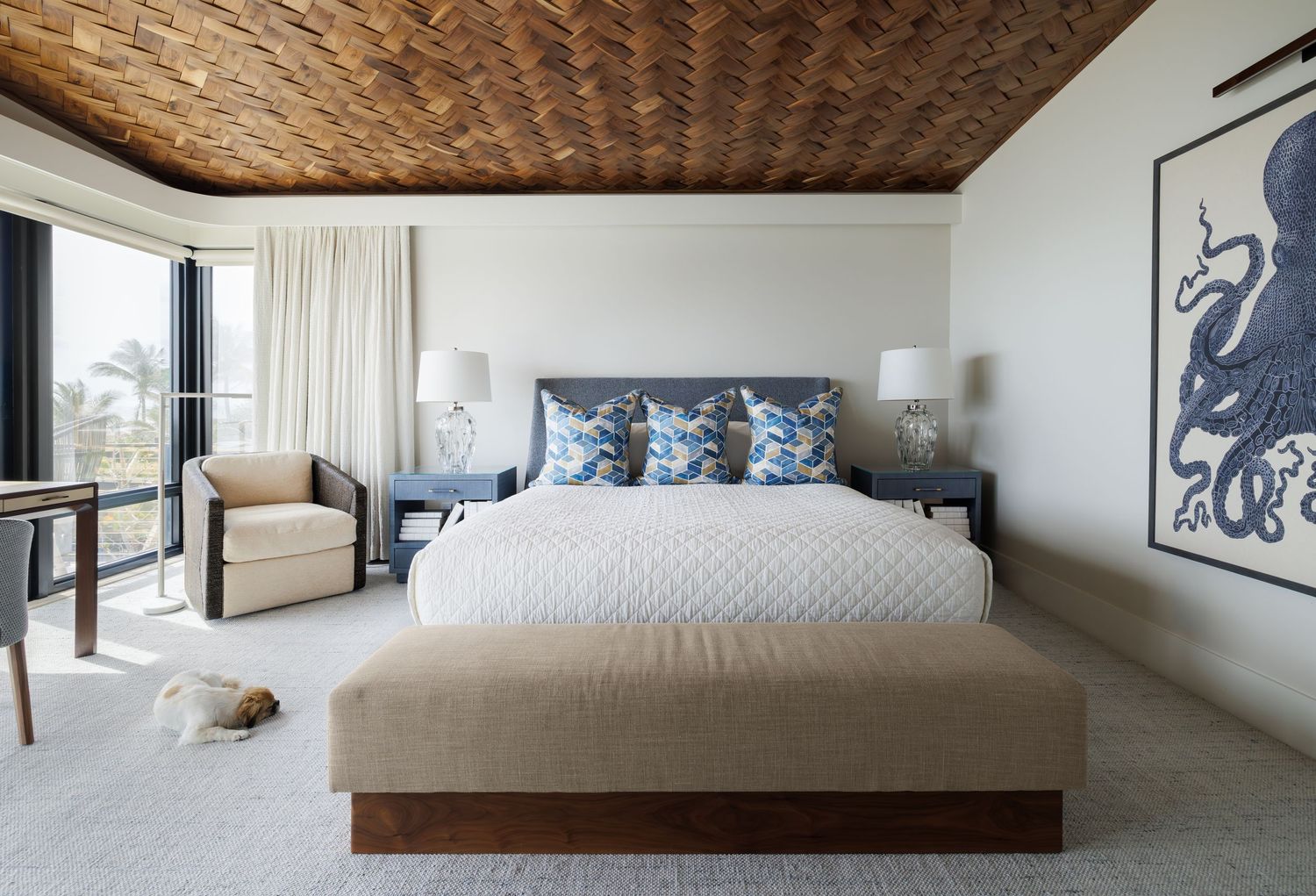 Elegant coastal bedroom with woven wood ceiling, blue accents, and octopus wall art.