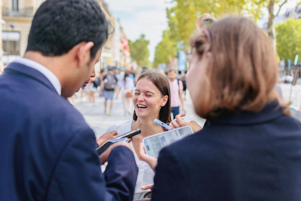 Young woman laughs joyfully during an outdoor interview on a sunny city street.