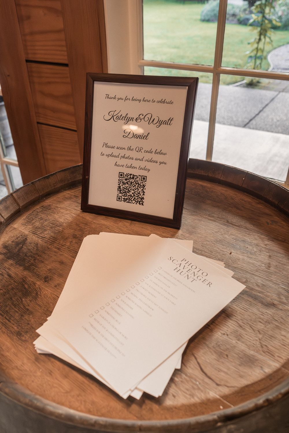 Wedding reception setup with QR code signs and paper details displayed on a rustic wooden barrel surface.