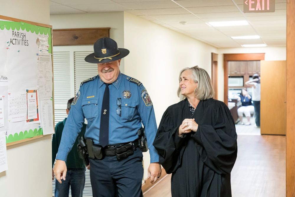 Law enforcement officer and Chief Justice Sarah Hicks Stewart walking through a hallway.