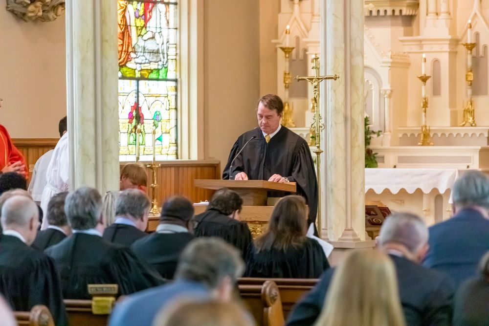 Church congregation gathered in pews during a religious service with stained glass windows visible.