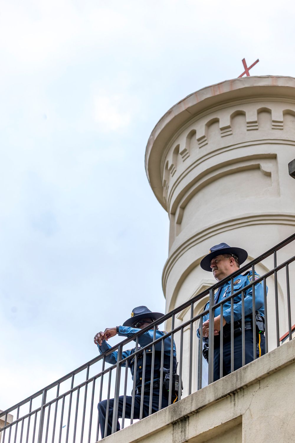 People observing from a curved balcony railing against a cloudy sky.