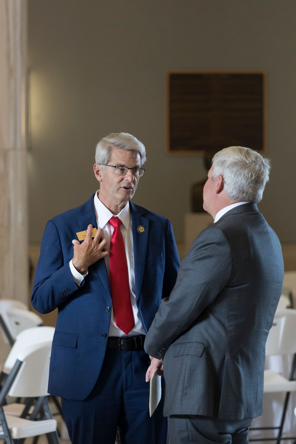 Two men in business attire having an animated conversation in an indoor setting.