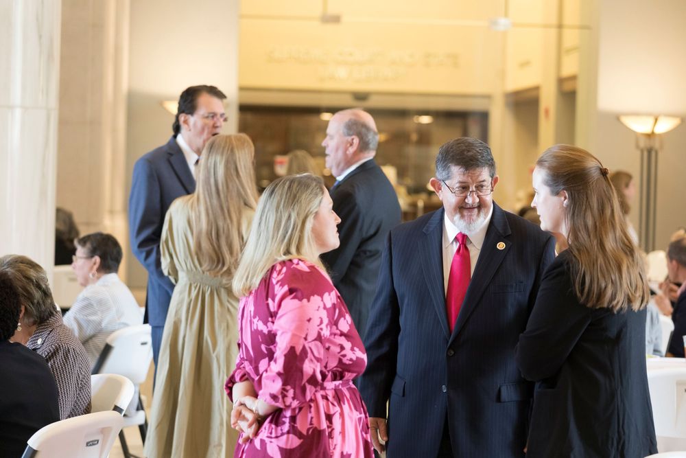 People mingling in a hallway with classical architecture and warm lighting.