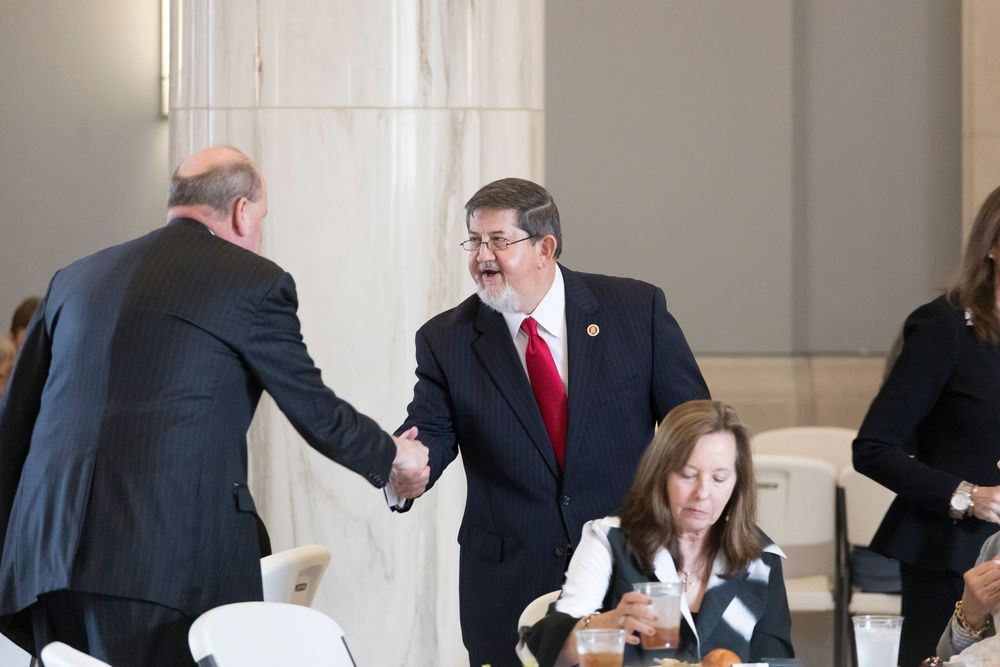 Business professionals engaged in conversation during a networking event in a bright hallway.