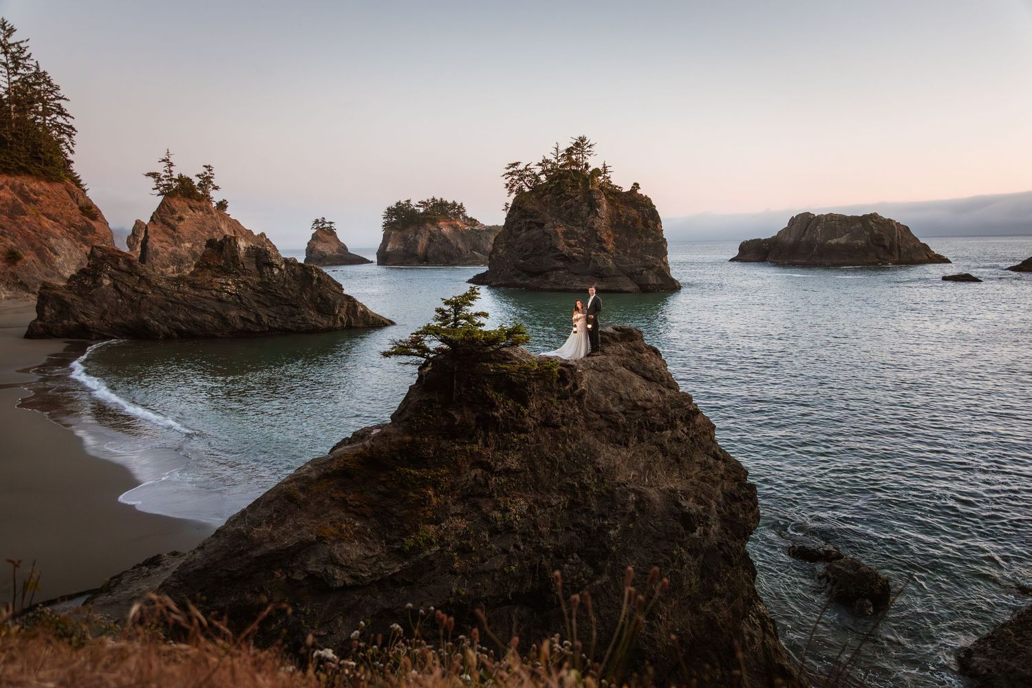Couple eloping on dramatic sea stacks at sunset on the Oregon coast.