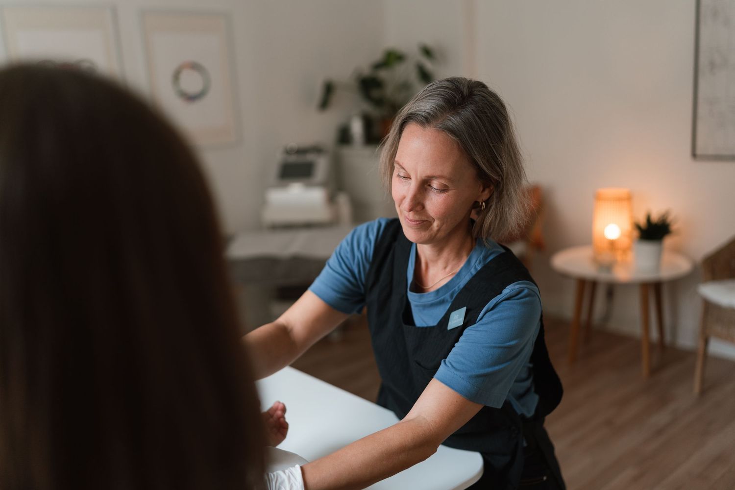 Person in blue shirt works at desk in home office with warm lighting and minimalist decor.