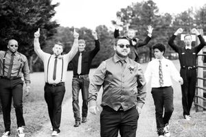 Groom and groomsman fun documentary style black and white photo during rustic farm outdoor wedding.