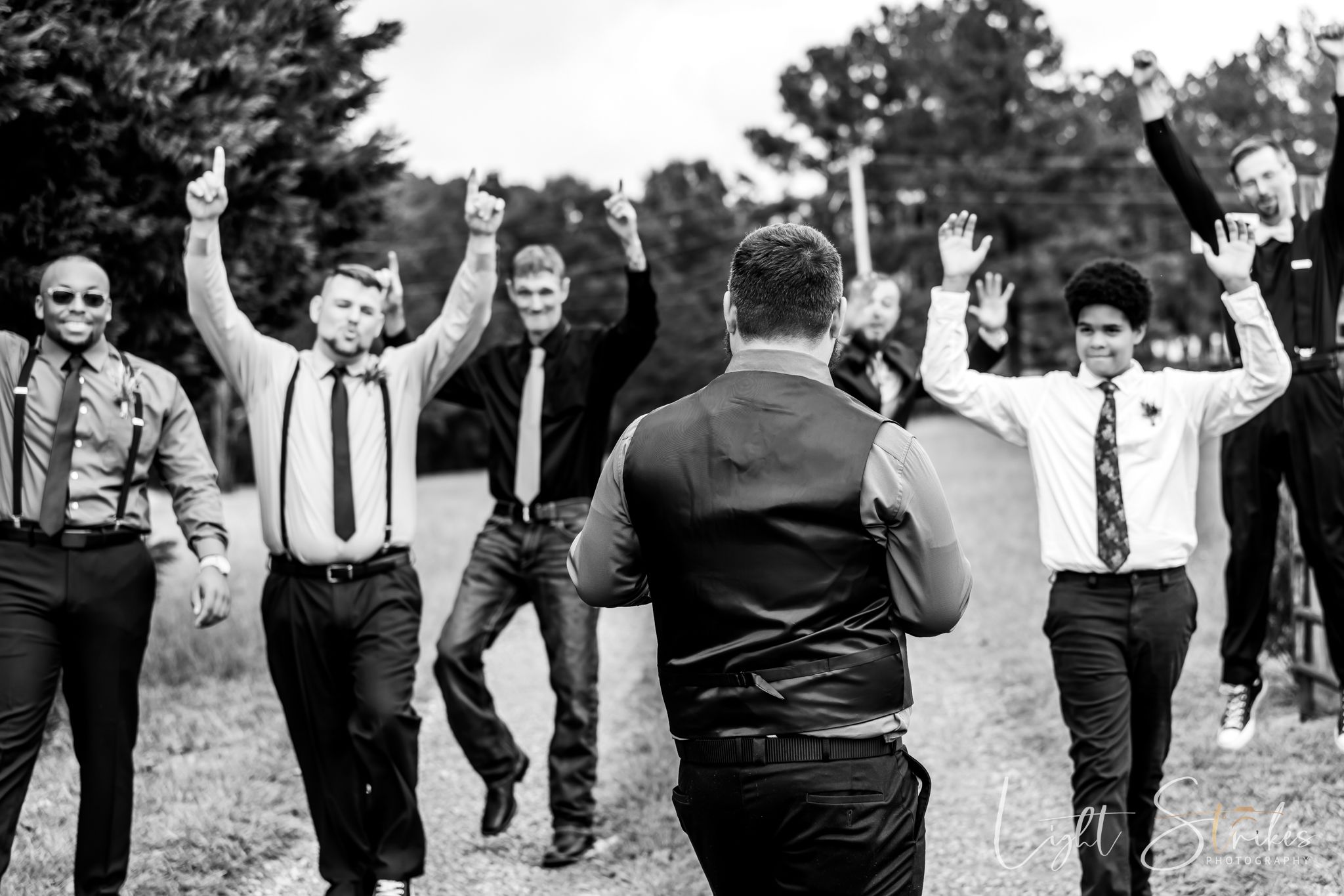 Groom and groomsman fun documentary style black and white photo during rustic farm outdoor wedding.