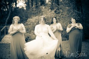 Vintage-style black and white wedding photo showing bride and bride mades in formal attire in an outdoor garden setting.