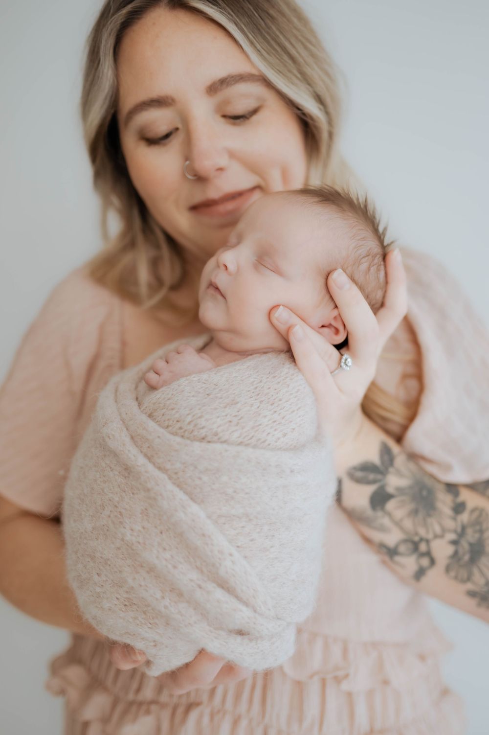 A series of intimate newborn photography poses showing a baby wrapped in soft cream fabric against a light background.