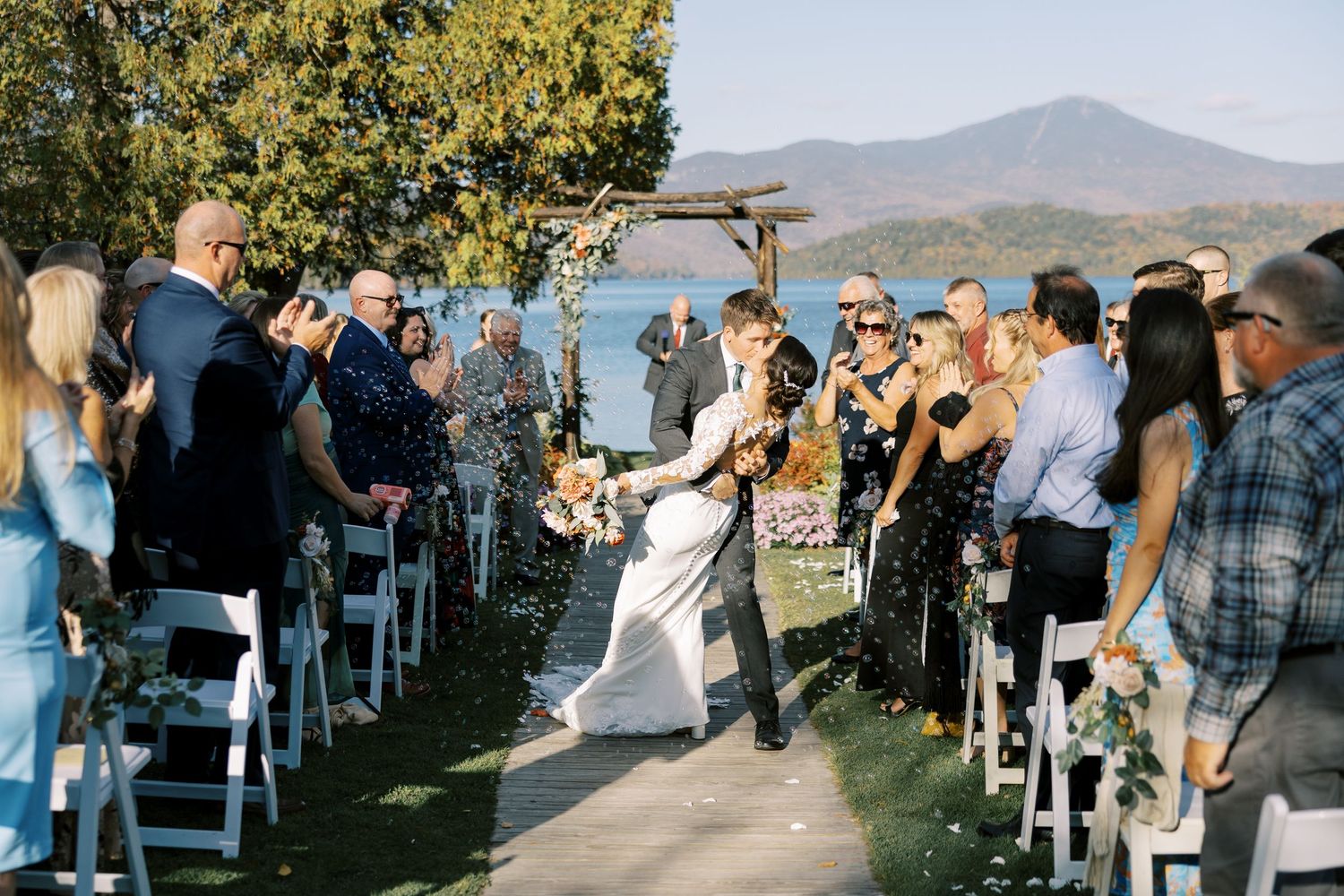 Outdoor wedding ceremony setup with white chairs arranged in rows overlooking a scenic mountain lake view.