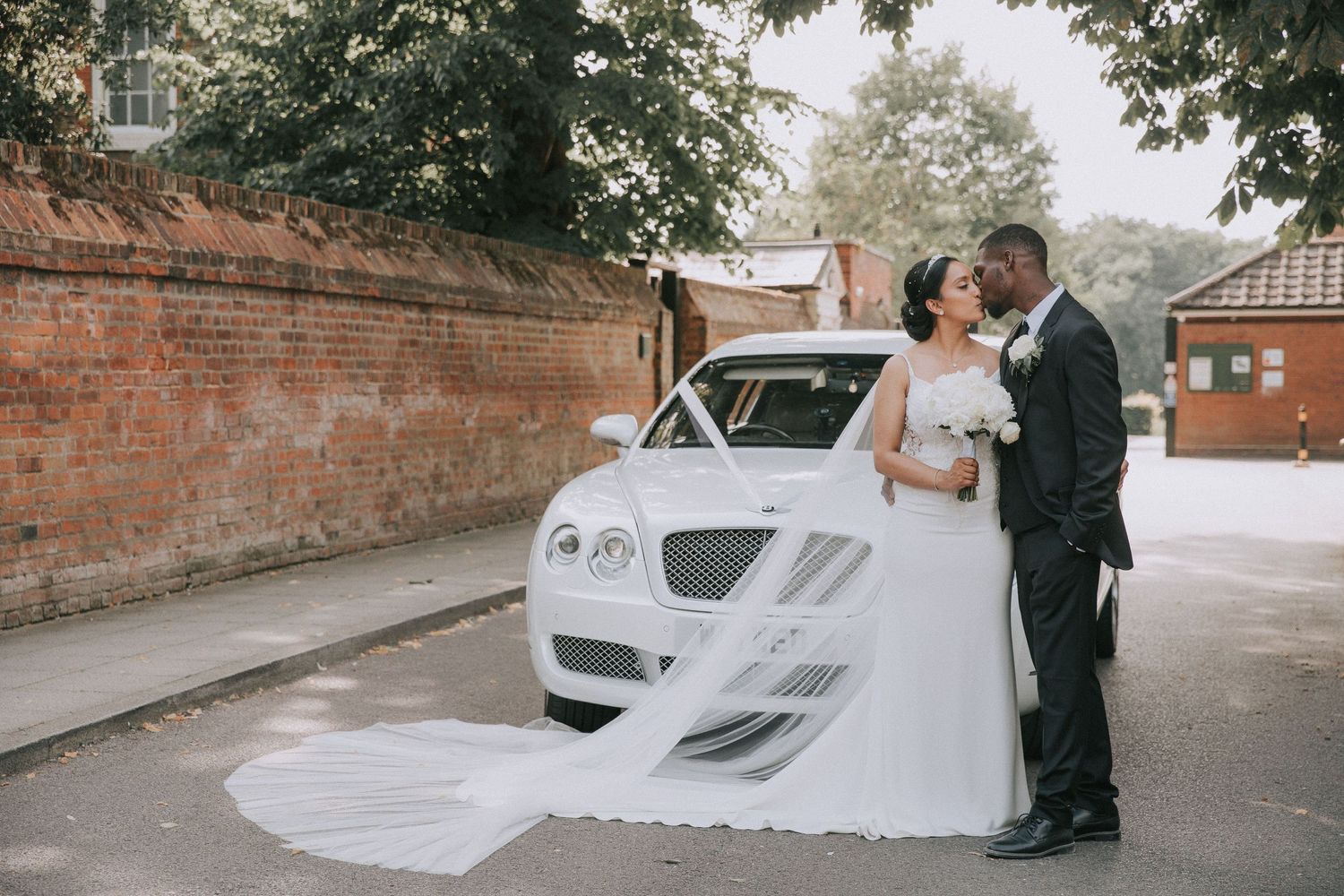 A series of wedding photos showing a couple next to a white car with flowing veil and brick wall backdrop.