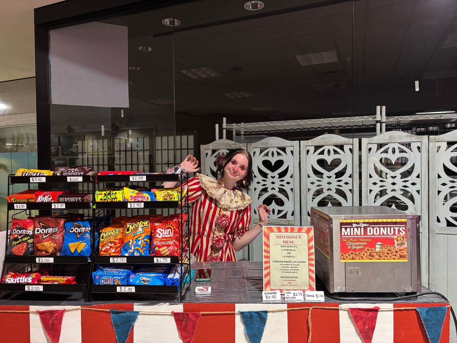 A concession stand at an event displays snacks and candy with red and white striped decorative elements.