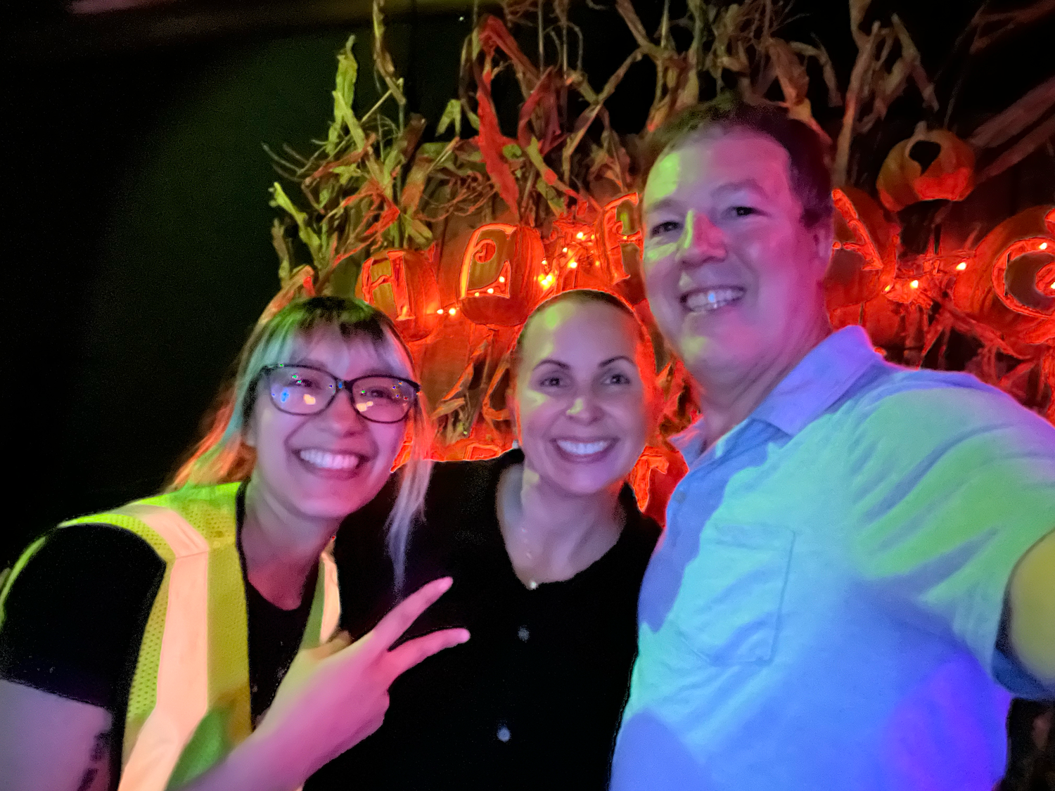 People are enjoying themselves at a haunt with colorful red and green lighting effects in the background.
