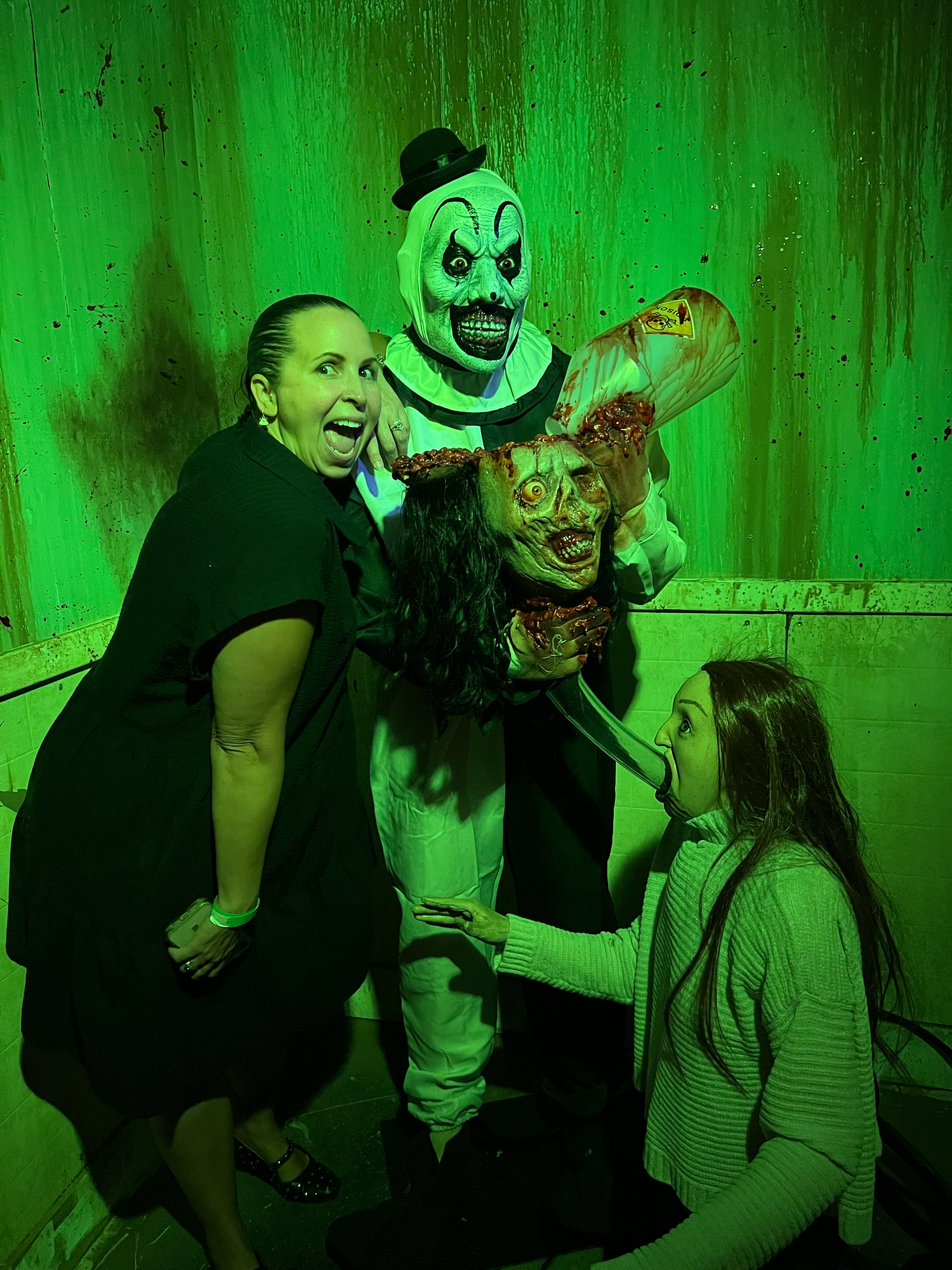 A series of four photos showing people in Halloween costumes posing with spooky green lighting effects with Art the clown