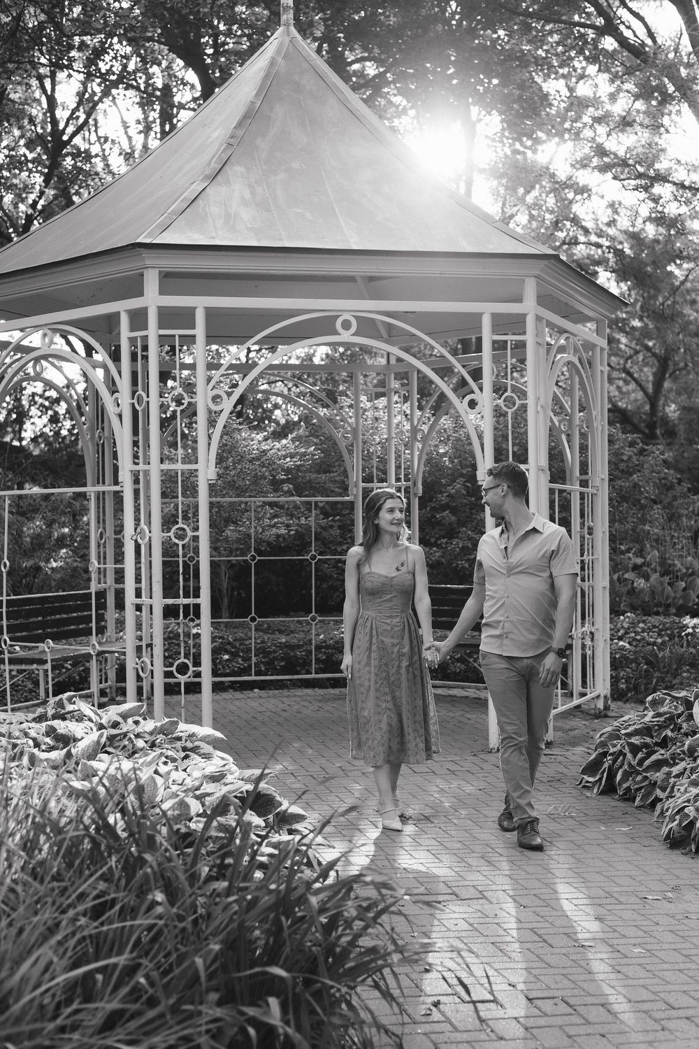 A series of black and white photos showing a couple in a garden gazebo with brick paving and landscaping.