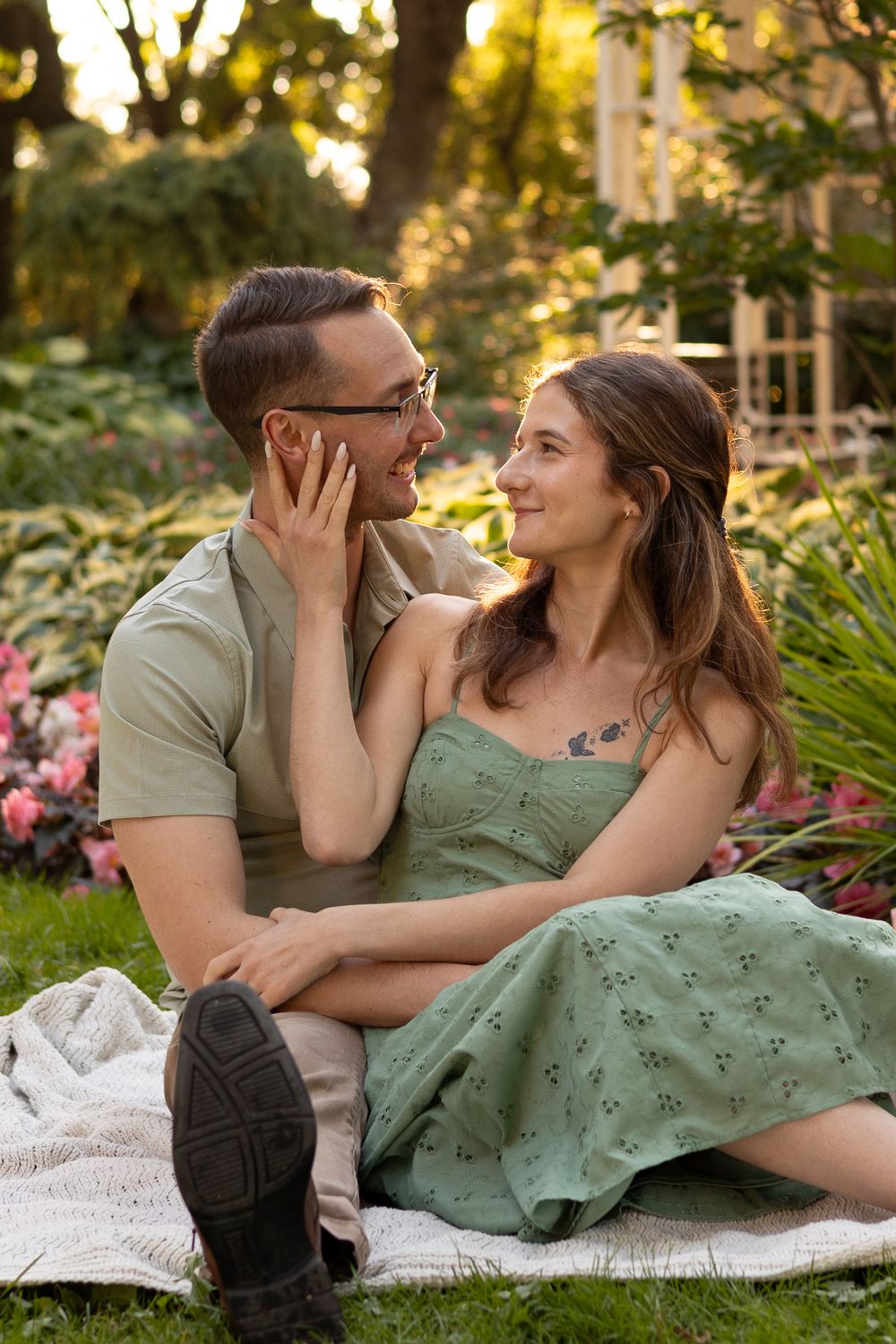 A romantic couple shares intimate moments on a blanket in a garden setting during golden hour.