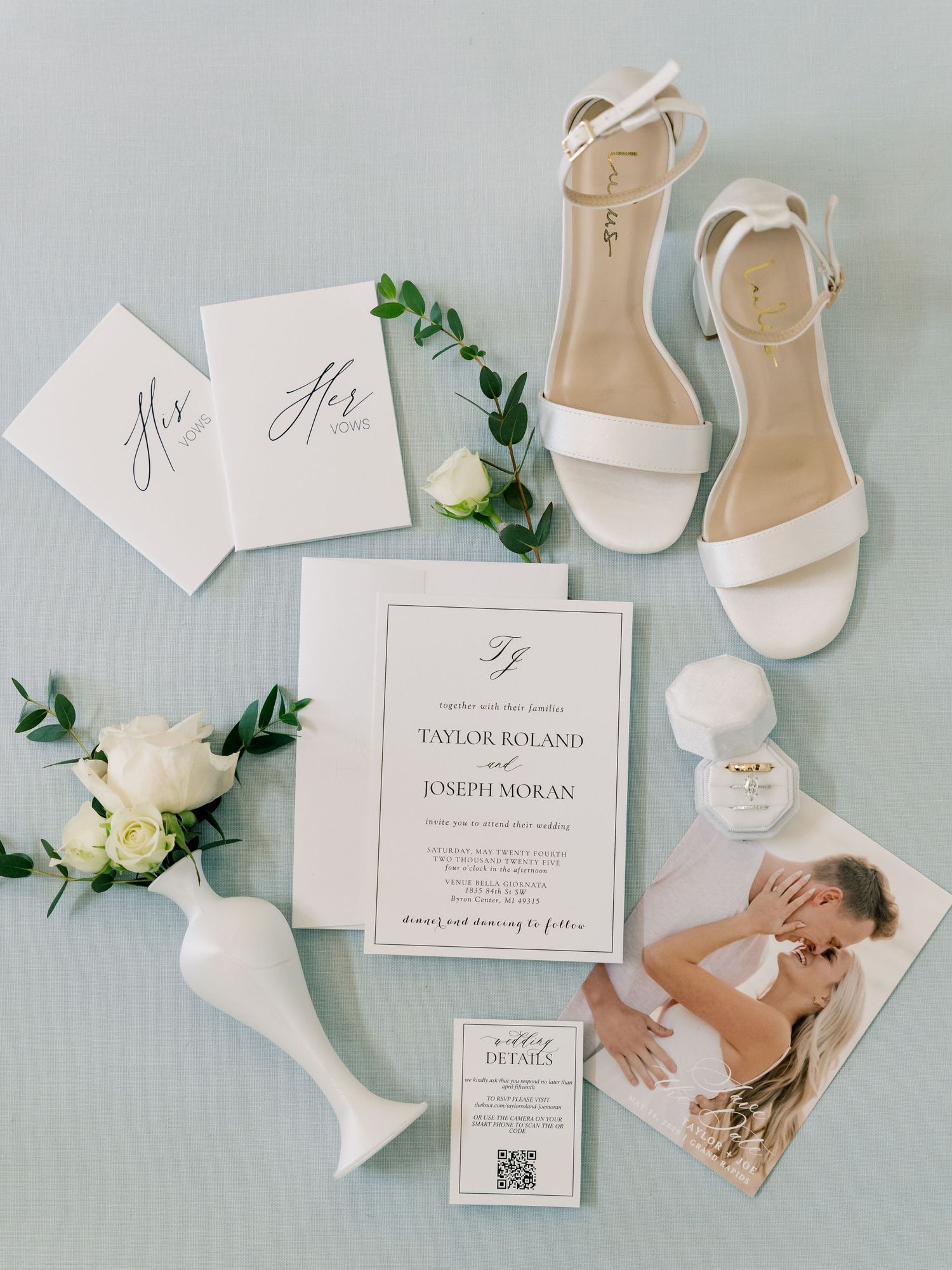 Wedding details flatlay with white shoes, invitations and floral accents.