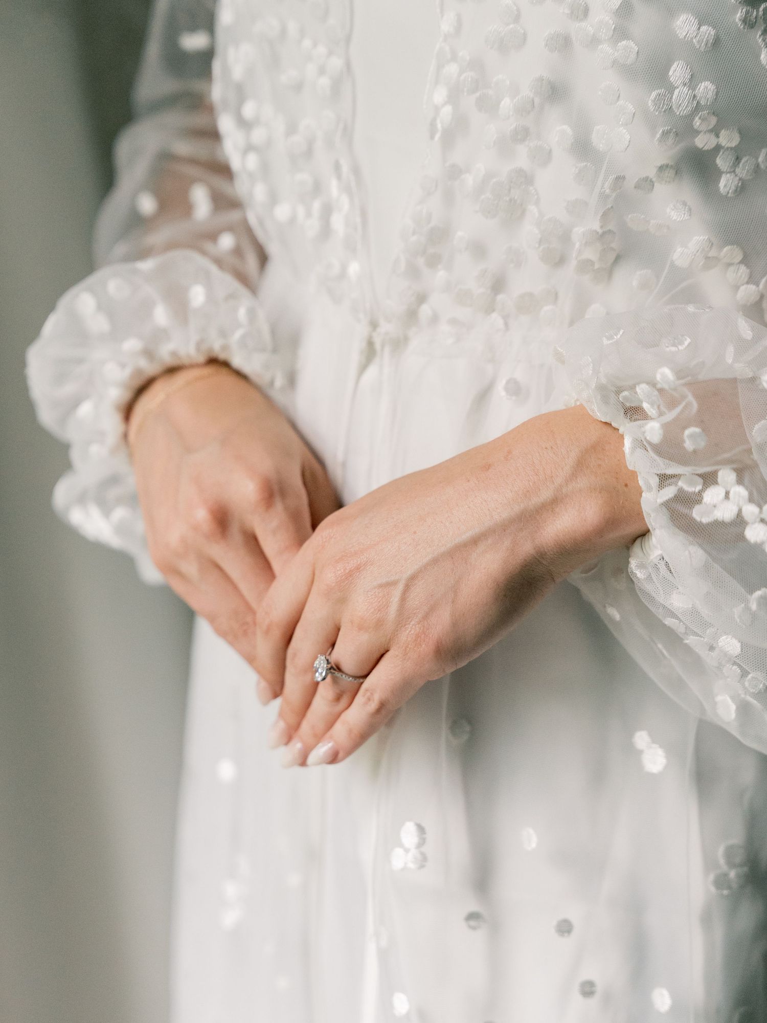Close-up details of delicate floral appliques and lace on white wedding dress sleeves.