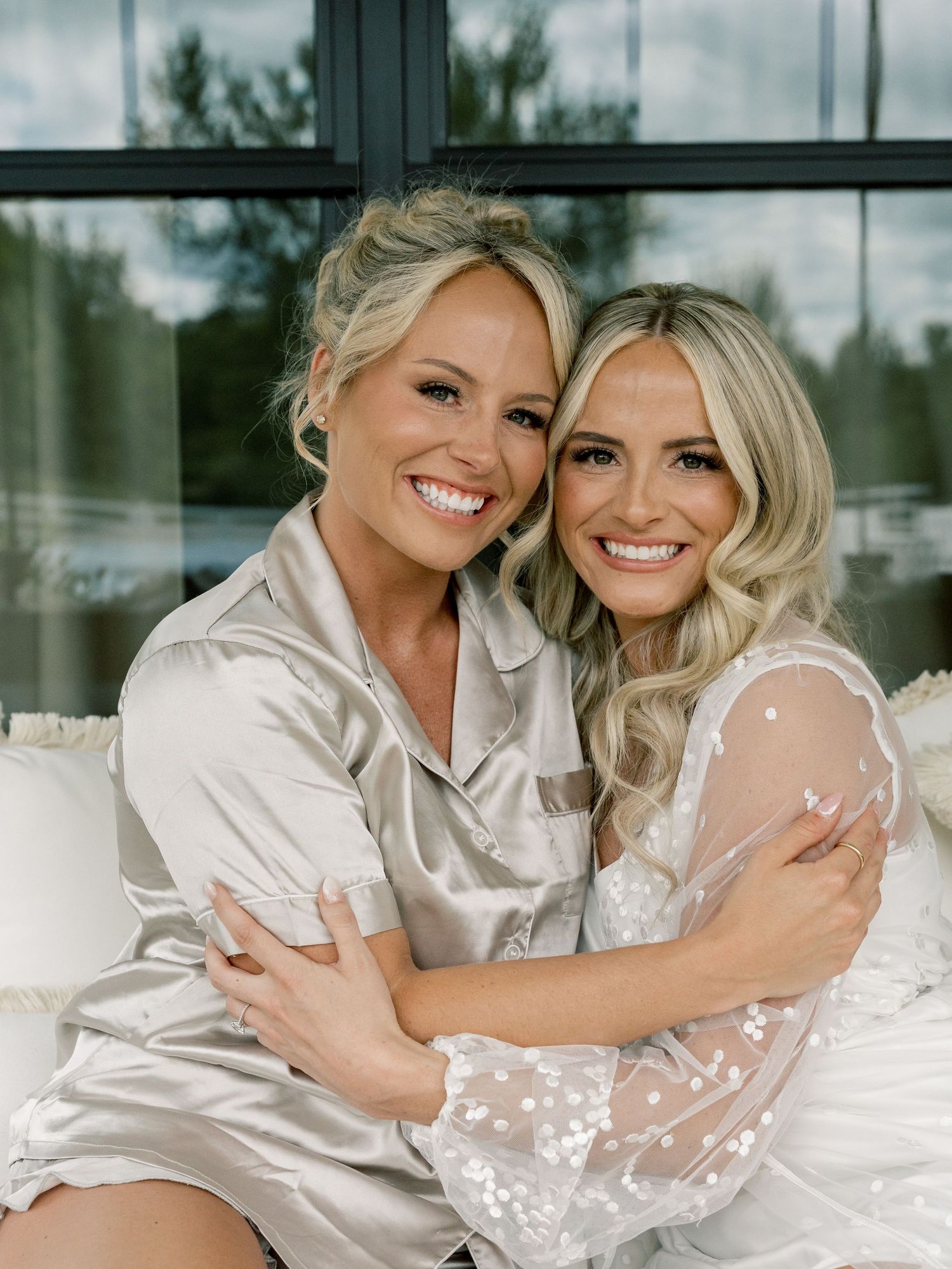 Two people embracing in white robes during wedding day preparations.