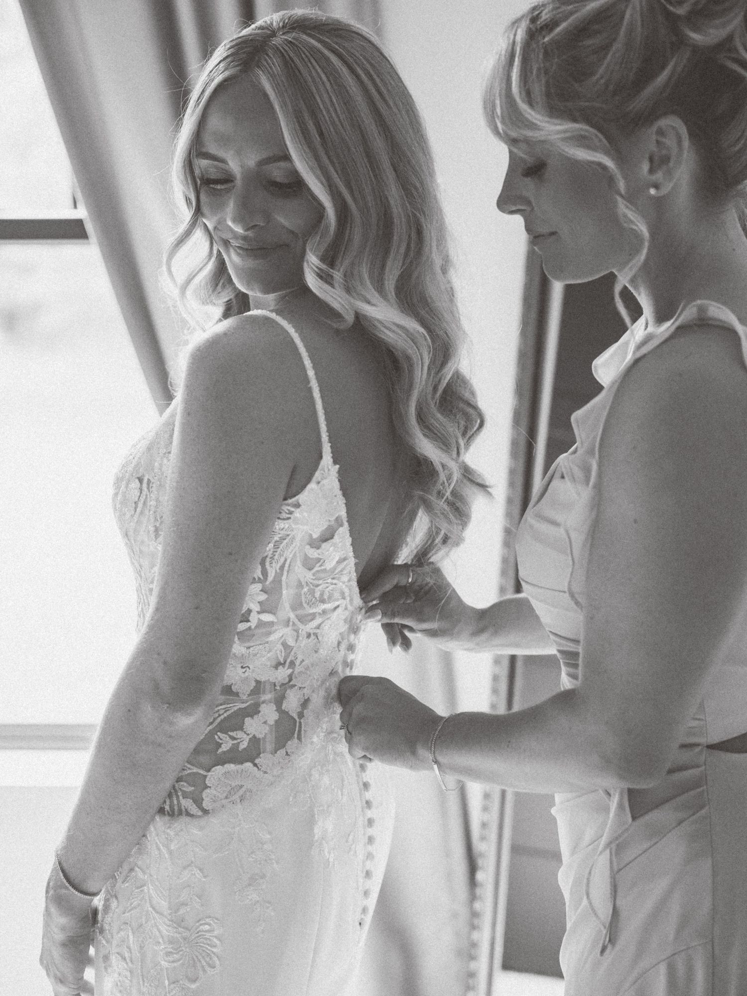 Black and white photo of wedding dress preparations with elegant lace details.