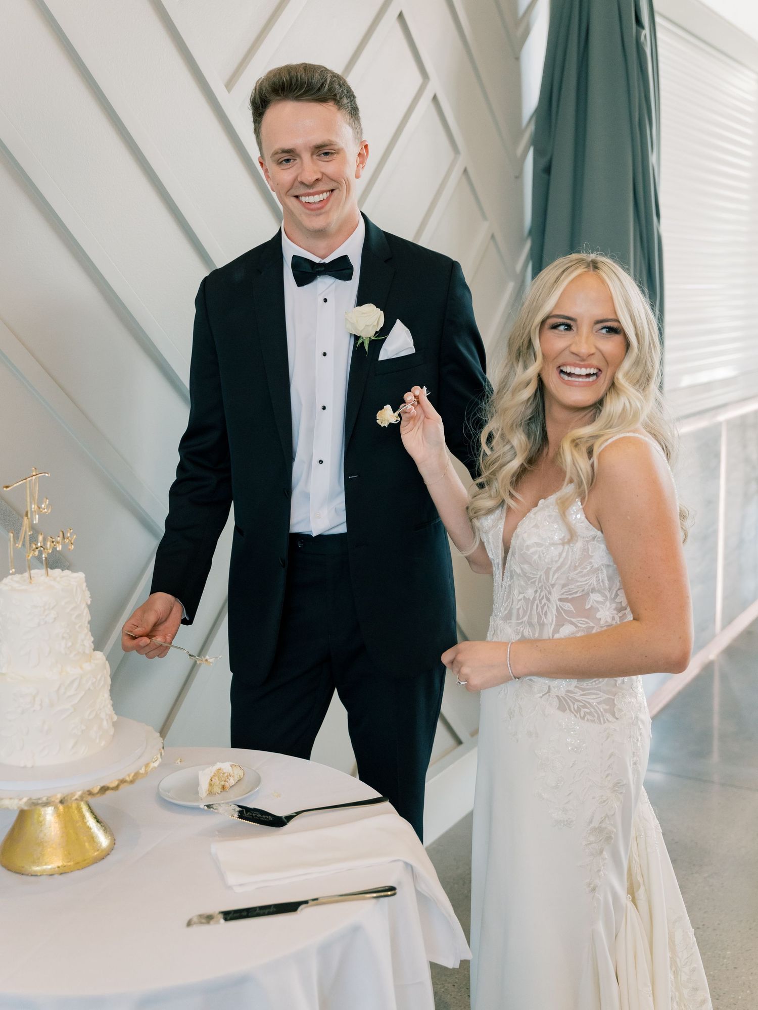 Wedding cake cutting celebration with a classic white tiered cake on a gold stand.