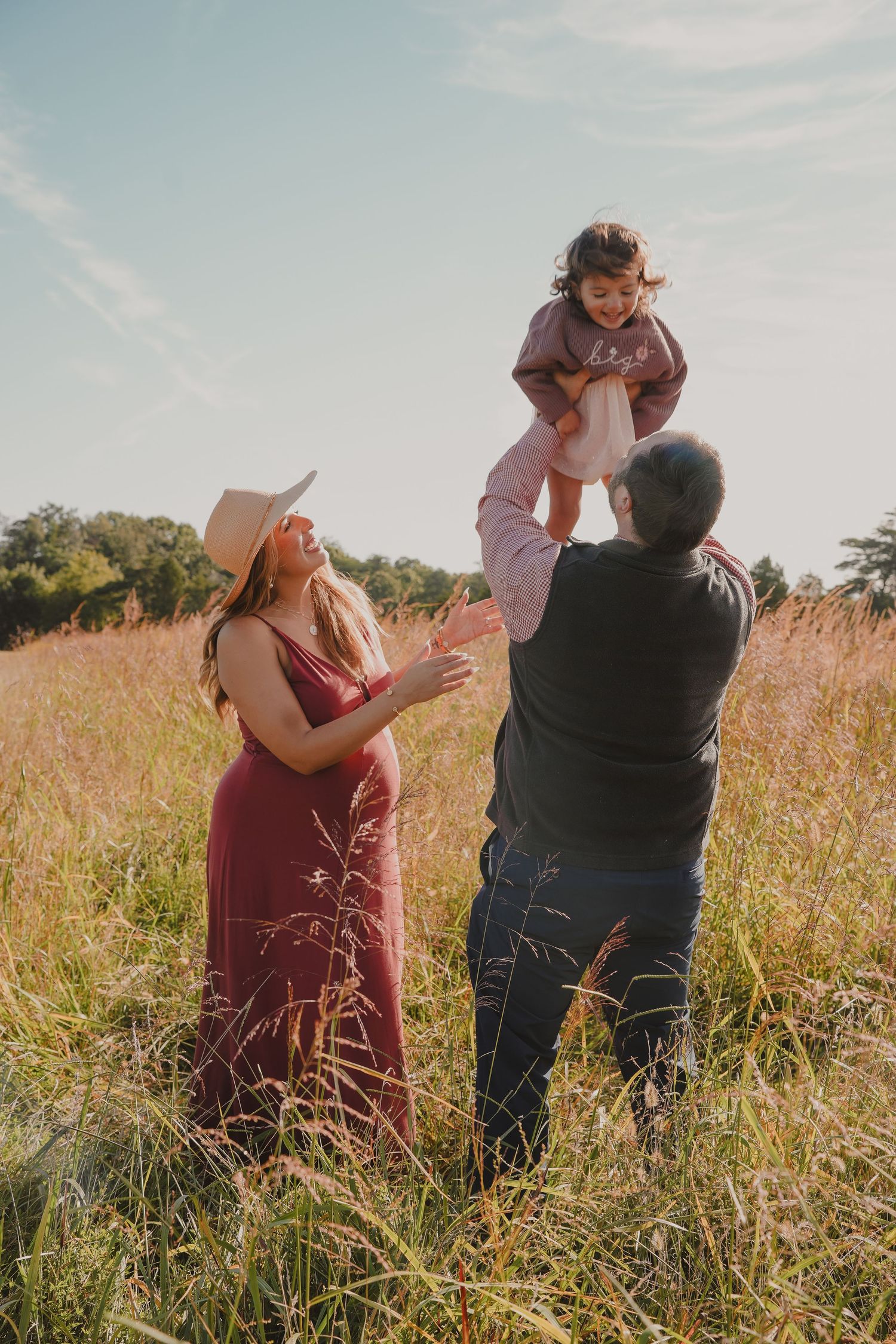 Family enjoying playful moments together in a golden field during sunset.