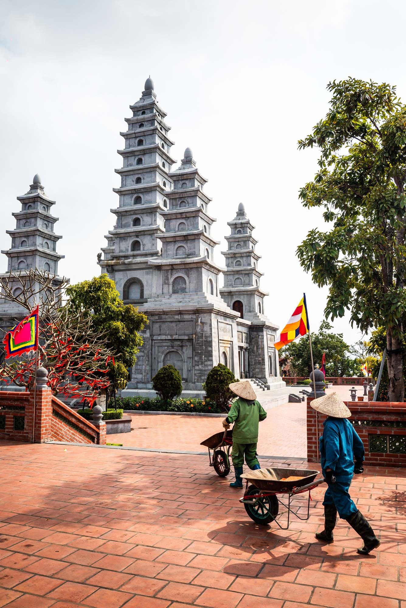 People walking up stone steps towards ornate white Buddhist pagodas at Linh Ung Pagoda in Da Nang, Vietnam.