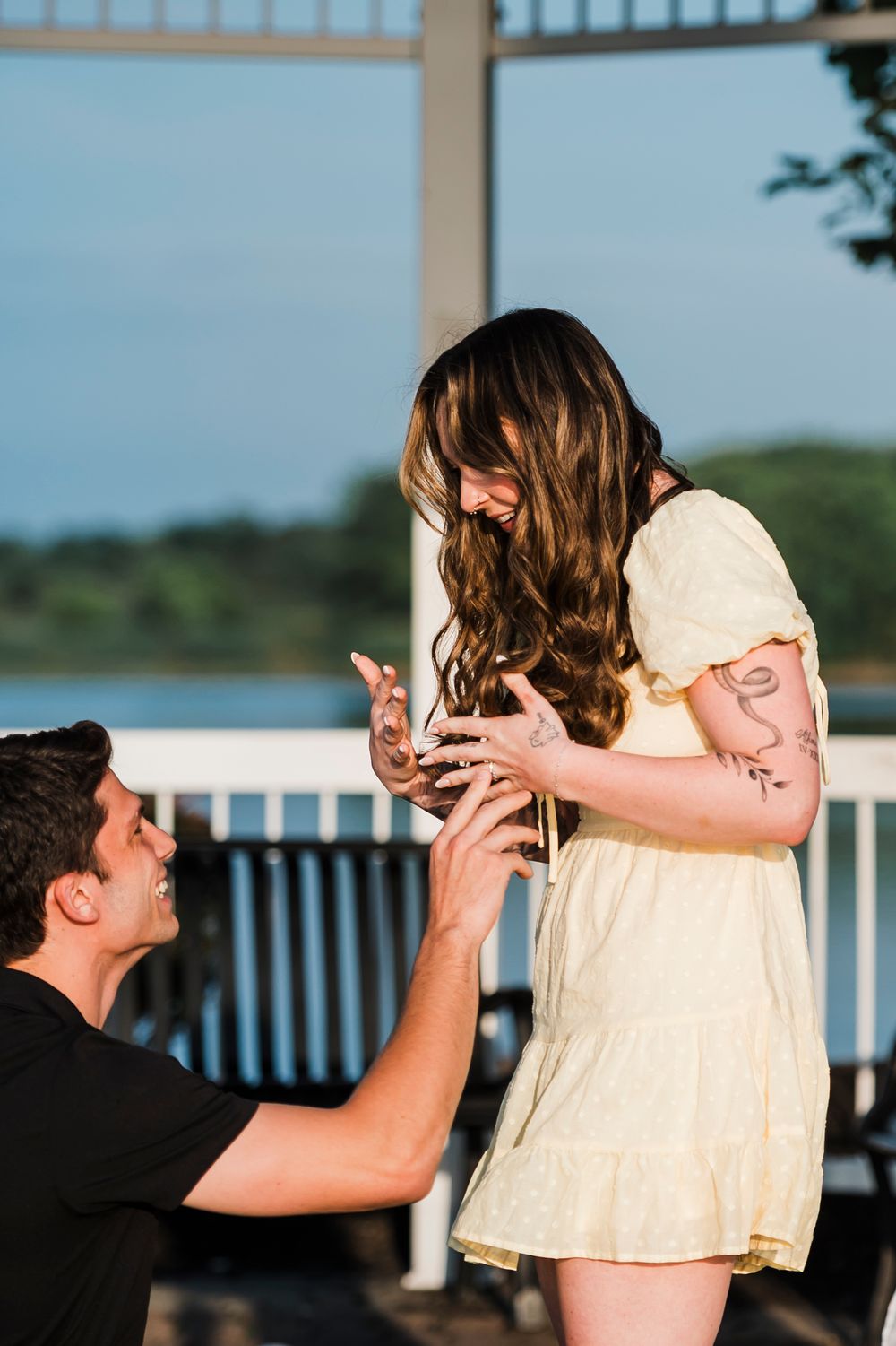A romantic couple shares a tender dip dance pose against a waterfront backdrop with railings.
