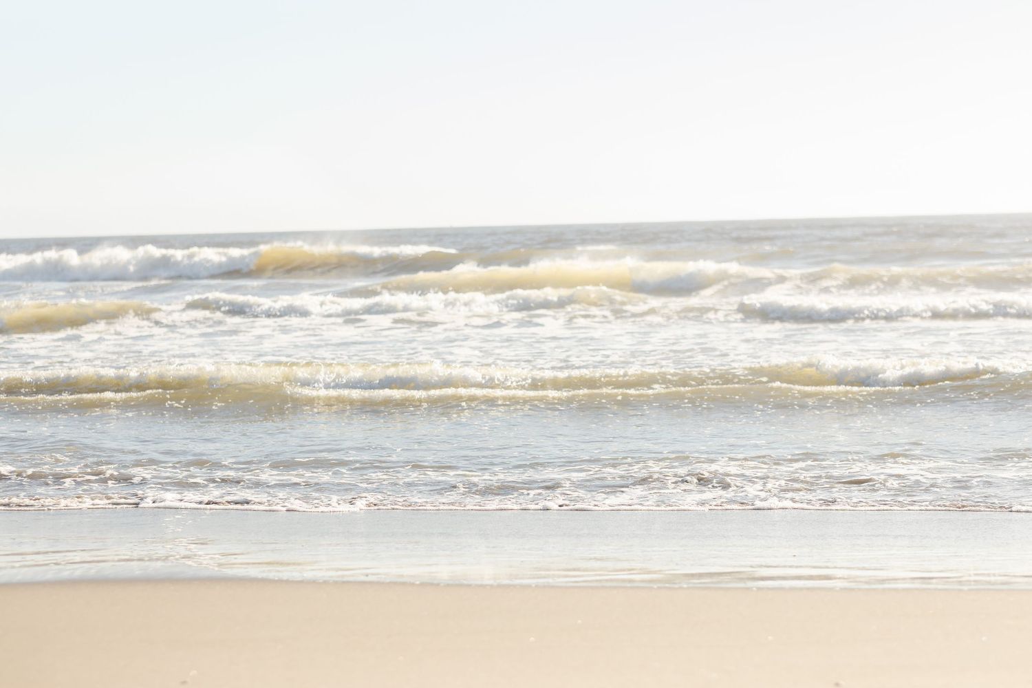 Ocean waves crash onto a sandy beach during sunset creating a serene coastal landscape.Film by Chelsee Rawe Photography