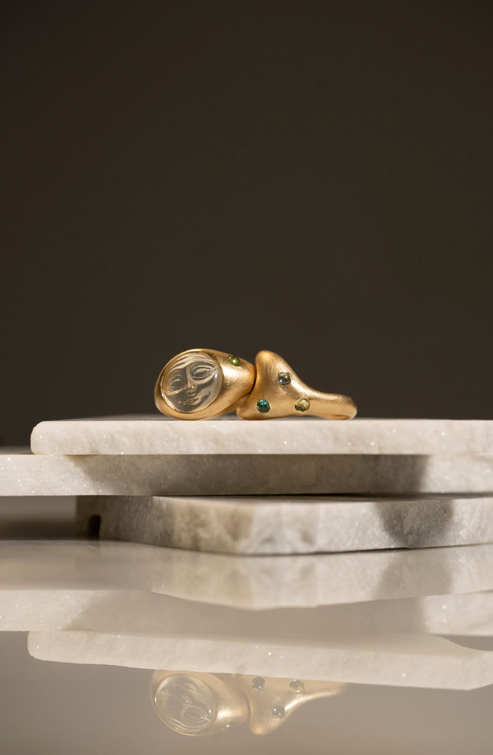Gold jewelry displayed on marble with warm shadows; Autumn/Winter luxury brand photography in a Florence studio.