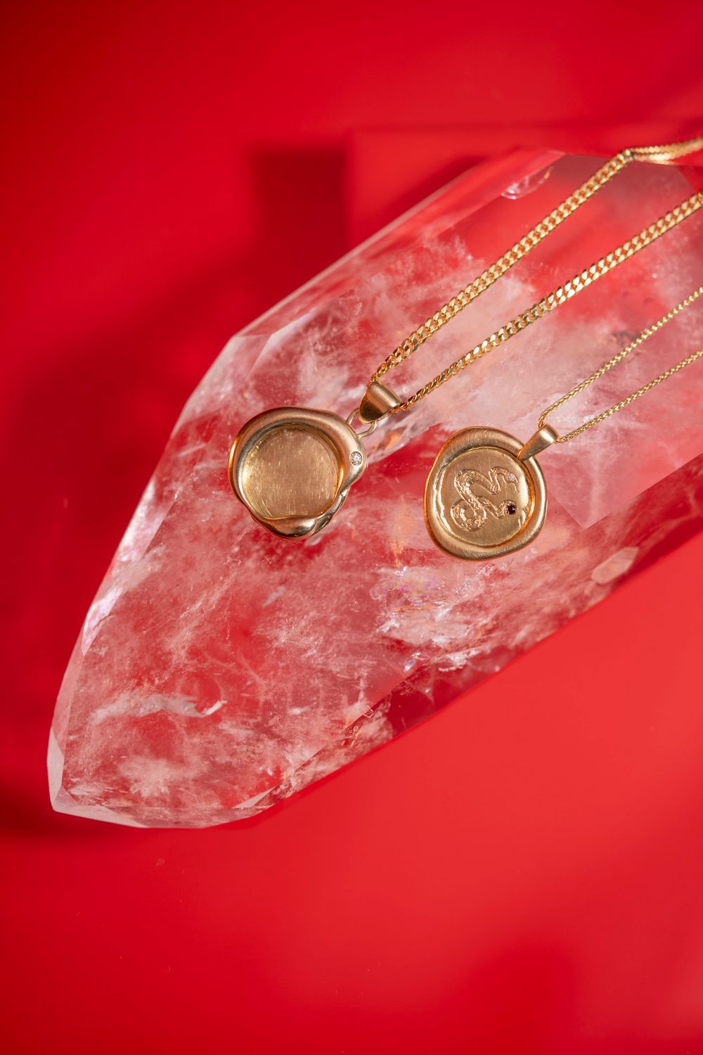 Vibrant macro shot of gold earrings on a red crystalline surface; commercial jewelry photography for high-impact social media ads.