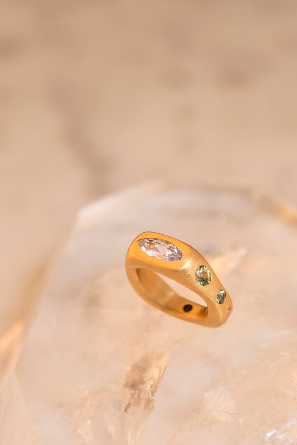 Warm, glowing macro shot of a gold ring on ice or crystal; creative jewelry product shots with high-end lighting techniques.