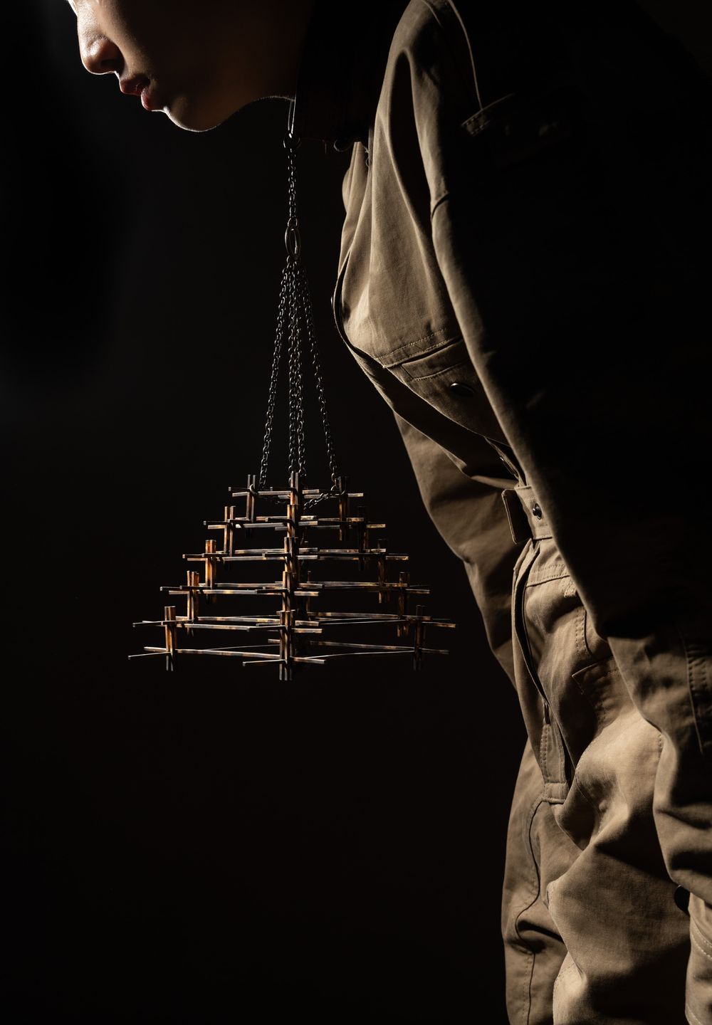 Moody, low-key lighting of a hand holding a beaded accessory; artistic product storytelling for international fashion campaigns.