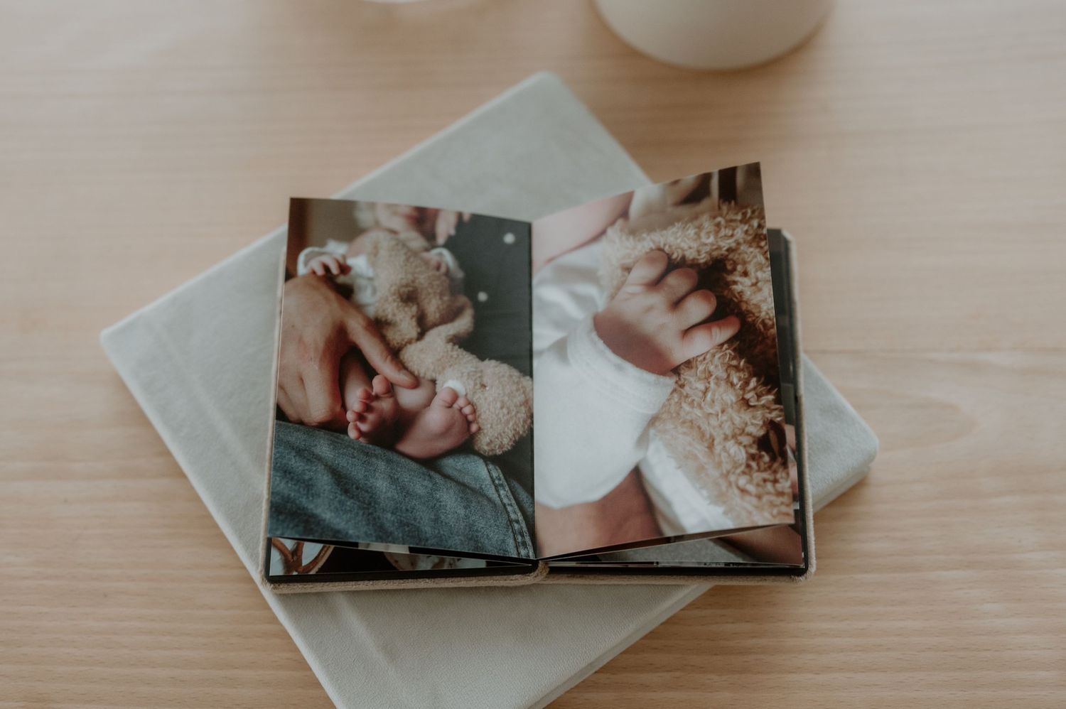 Open fotoalbum met meerdere familiefoto’s op een houten ondergrond, vastgelegd in zacht natuurlijk licht.