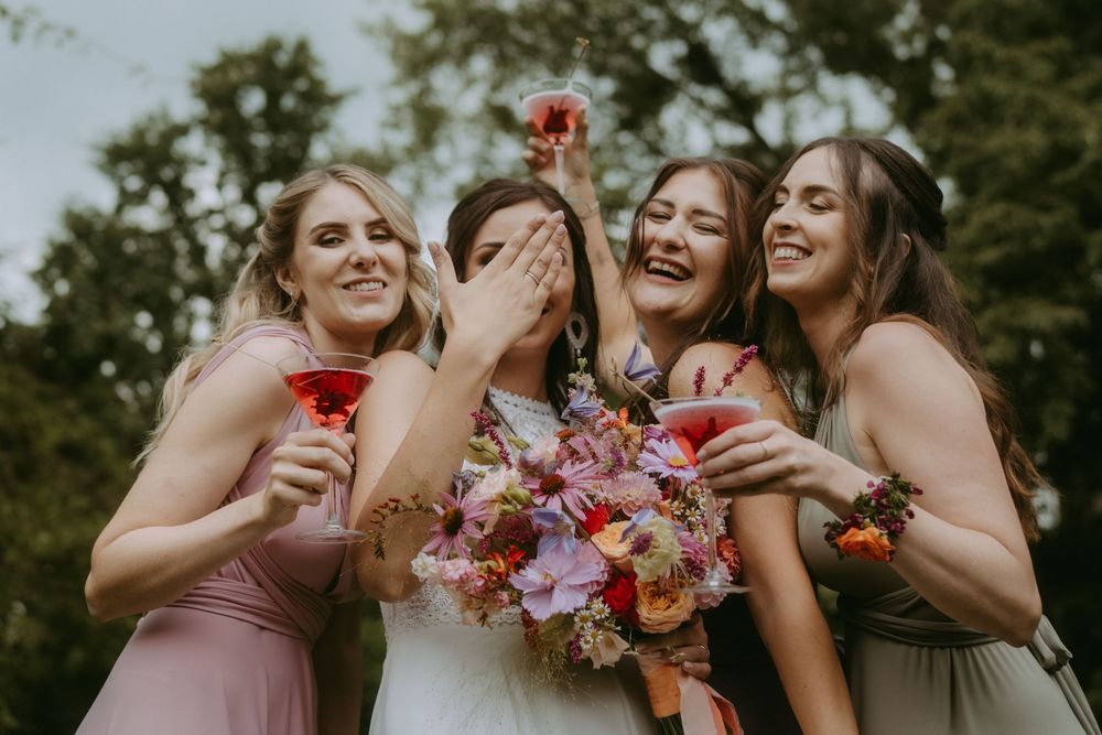 Wedding party shares laughs and drinks during outdoor celebration.